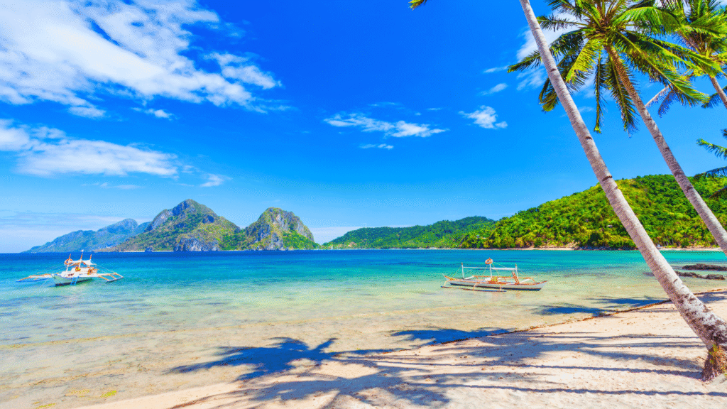 Scenic view of El Nido beach with turquoise waters, karst limestone cliffs, and a traditional Filipino boat floating near a secluded lagoon in Palawan, Philippines

