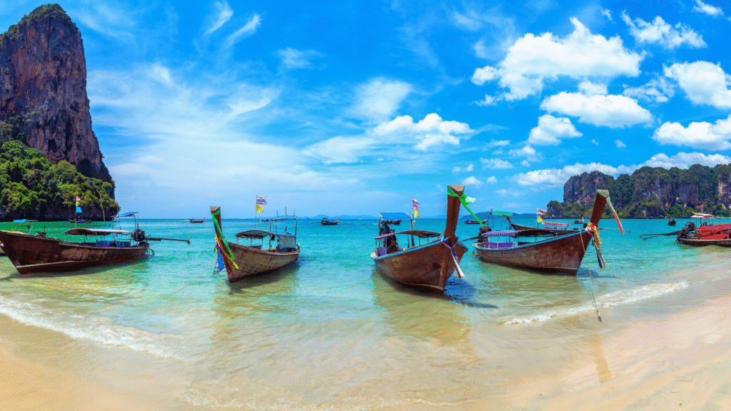 Aerial view of Railay Beach in Krabi, Thailand with turquoise water, dramatic limestone cliffs, and travelers kayaking near the shore – one of the Top 10 Asian Beaches

